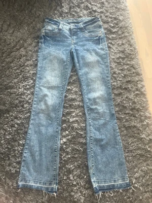 Blå bootcut jeans från Rainbow - Snygga ljusblå bootcut jeans från Rainbow med klassisk femficksdesign och markerade sömmar. Jeansen har en något utsvängd passform nertill och normal midja. Perfekta för dig som gillar en retroinspirerad look.