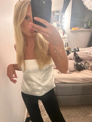 Vit bandeau topp med knytband - Säljer en stilren vit bandeau topp med knytband i sidorna som man knyter där bak. 