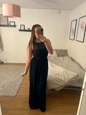 Marinblå balklänning med spetsdetalj - Marinblå balklänning från Nelly med transparent mesh upptill,  fin spets i ryggen och markerad midja. Den är i storlek 36 och endast använd en gång. Passar perfekt till bal eller festligare tillställningar! (Original pris 699)