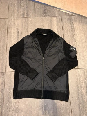 Svart J.Lindeberg cardigan - Säljer en J.Lindeberg cardigan i svart. Den är sjukt snygg och kan stylas till många outfits, perfekt till våren, sommaren o hösten. Har använt den några gånger men den har inga skador på sig.