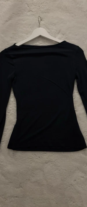 Svart långärmad topp - En stilren svart långärmad topp med figurnära passform. Perfekt att matcha med jeans eller kjol för en enkel och snygg look. Tunn och mjuk i materialet, passar året runt.