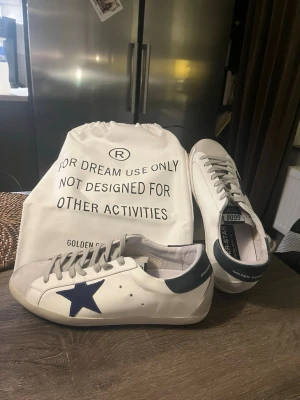 Golden Goose vita sneakers med blå stjärna - Ett par riktigt snygga Golden Goose i storlek 42🌟 Riktigt bra skick, knappt använda! OG Dustbag fås med! Självklart äkta! (KVITTO FINNS)
