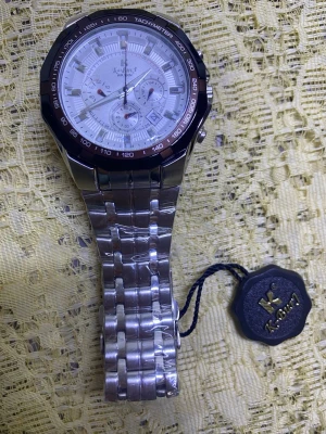 Kademan silverfärgad kronografklocka - Stilren klocka från Kademan med silverfärgad länk i metall och vit urtavla med flera små urtavlor och tachymeter. Klockan har en sportig känsla och detaljerad design, perfekt för dig som gillar accessoarer med lite extra funktion. Nya klockan med nya batteri 