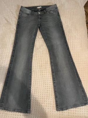 Grå bootcut jeans från Gina Tricot - Snygga grå bootcut jeans från Gina Tricot med klassisk femficksmodell och låg midja. Jeansen har en tvättad look med ljusare partier och vida ben. 