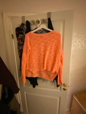 Korallrosa stickad tröja - Mysig stickad tröja i en härlig korallrosa färg. Tröjan har en lös passform, rund halsringning och långa ärmar. Perfekt för lager-på-lager och chill dagar. Materialet känns mjukt och lätt, vilket gör den skön att bära. Är i m men sitter som S