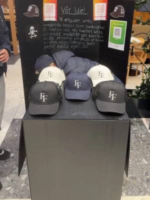 Svart Flexfit keps med broderad logga - Snygg svart keps från Flexfit med böjd skärm och vit broderad FF-logga framtill. Klassisk trucker-modell med mesh på sidorna och justerbar snapback baktill. Tillverkad i slitstark bomull och polyester för en bekväm passform.