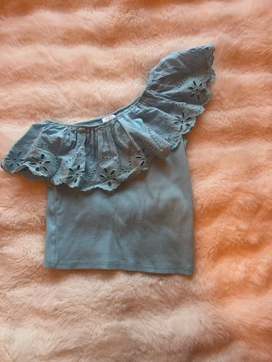 Blå offshoulder topp från Zara - Snygg blå offshoulder topp från Zara med volang och broderade blommor längs axeln. Luftigt material och cool design. 11-12 år🩷