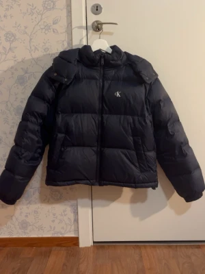 Calvin Klein pufferjacka - Säljer jackan eftersom att den är för liten för mig, jackan är relativt ny och har inga defekter. Den är mörkblå och lite croppad. Nypris: 1400kr. Skriv för frågor 💕