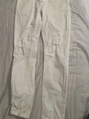 Vita Dsquared2 jeans - Snygga vita jeans med raka ben och slitningar vid knäna. Jeansen har klassisk femficksdesign och är tillverkade i ett bomullstyg med lite stretch. Perfekta för en fräsch och trendig look.