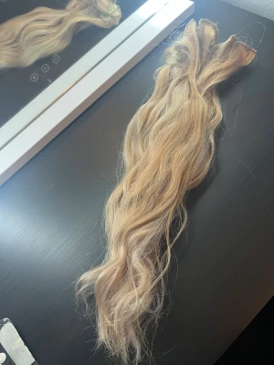 50cm blond Clip on hårförlängning  - Clip-on hårförlängningar i färg #613, längd 50 cm. 100 gram 7 delar i fint skick. Vissa delar saknar spännen 