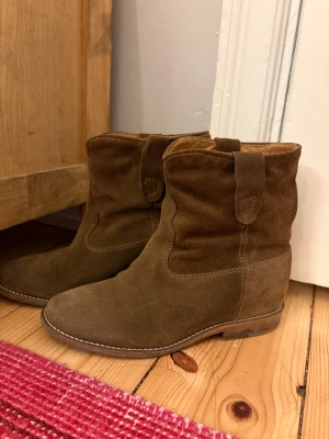 Bruna mocka cowboy boots Isabel Marant - Snygga bruna cowboy boots från Isabel Marant i mjuk mocka med rund tå och klack sula. Bootsens klassiska western-detaljer och sömmar ger dem en cool vibe. Insidan är fodrad i skinn för extra komfort. Perfekta för dig som gillar avslappnad stil med edge.