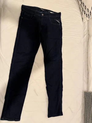 Mörkblå Replay jeans slim fit - Snygga mörkblå jeans från Replay med klassisk femficksdesign och diskreta sömmar. Jeansen har en slim passform och är tillverkade i stretchigt denim för extra komfort. Perfekta för dig som gillar en stilren look med smal siluett.alldrig använda 