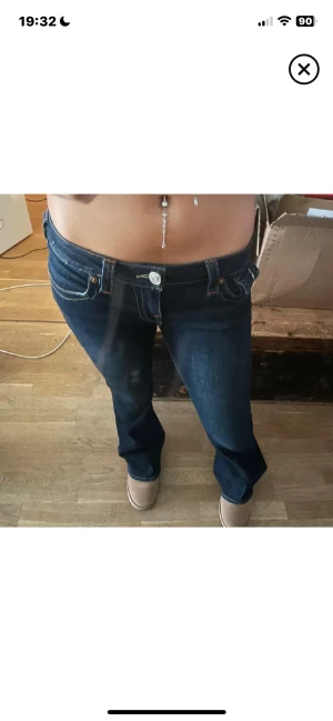 Mörkblå True Religion jeans bootcut - Snygga mörkblå jeans från True Religion med bootcut och låg midja. Klassiska kontrastsömmar, stora fickor bak med dekorativa knappar och logga. Jeansen är i kraftigt denimtyg och har en riktigt schysst passform som ger en cool siluett. Köpta för 1200 och använda ett par väldigt fåtal gånger!💗