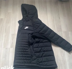 Svart quiltad pufferjacka från Nike - Säljer en svart pufferjacka från Nike med huva och dragkedja framtill. Jackan har ett quiltat mönster och den klassiska Nike-loggan i vitt på bröstet. Perfekt för kalla dagar och riktigt snygg streetstil. Jackan säljs inte heller längre av affärerna, så passa på nu
