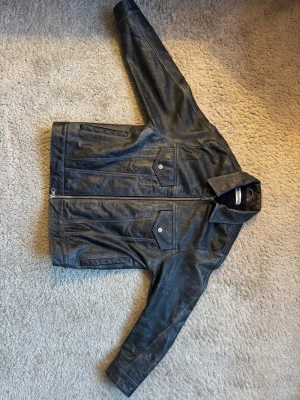 Svart skinnjacka med dragkedja - Säljer en svart skinnjacka från Cole Buxton, tvättad svart/grå färg som är väldigt unik. Finns inte längre kvar att köpa så därav väldigt svår att få tag på. Använd ca 5/6 gånger så väldigt fint skick. Köpte jackan för 7999kr och sydde då även in den för 2000kr. Storlek M och säljer den nu för 6000kr. Skriv för mer info om du är intresserad :) 