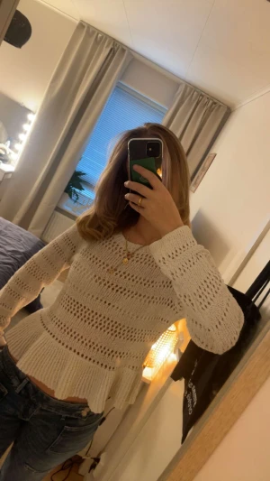 Vit stickad tröja med volang från H&M - Säljer en vit stickad tröja från H&M i storlek M. Tröjan har ett hålmönster, rund hals och långa ärmar. 