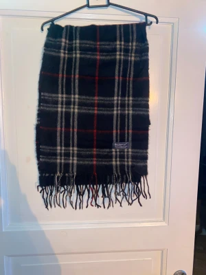 Svart Halsduk från Burberry - Svart halsduk från Burberry i 100% merinoull. Väldigt fint skick till ett bra pris. Mitt pris: 399kr
