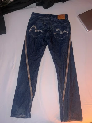 Evisu jeans  - Snygga blå jeans från evisu . Klassisk rak passform med coola broderade detaljer på bakfickorna och kontrastfärgade sömmar längs benen. 