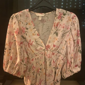 Blommig blus med puffärmar - Supersöt blus från H&M med blommigt mönster. v-ringning, puffiga trekvartsärmar och smock i midjan för en snygg passform. Använd ett fåtal gånger 