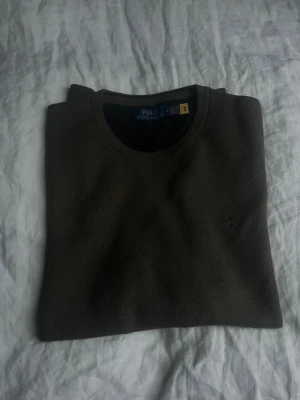 Olivgrön stickad tröja Polo Ralph Lauren - Snygg olivgrön stickad tröja från Polo Ralph Lauren med rund halsringning och diskret broderad logga på bröstet. Tröjan är aldrig använd.
