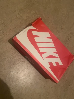 Nike sneakers svart/blå/rosa - Säljer ett par snygga Nike sneakers med svart ovandel, blå swoosh och rosa detaljer. Skorna har vit och rosa sula samt svarta skosnören. Perfekta för dig som vill sticka ut med färg och stil. Kommer i originalkartong.