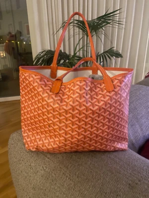 Orange shoppingväska  - Snygg och rymlig shoppingväska i orange med mönster. Väskan har två långa handtag och är i syntet. Perfekt för dig som vill sticka ut med en färgglad accessoar. Aldrig använd.