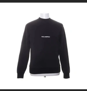 Svart sweatshirt från Karl Lagerfeld - Svart sweatshirt från Karl Lagerfeld med vit logotyp på bröstet och i nacken. Tröjan har rund hals, ribbade muddar vid ärmslut och nederkant samt lång ärm. Tillverkad i mjuk bomull för en skön och clean look.