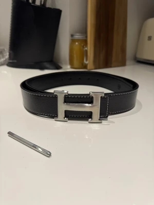 Svart H bälte  - Säljer ett svart H bälte. Helt nytt skick. Storlek 115cm. 