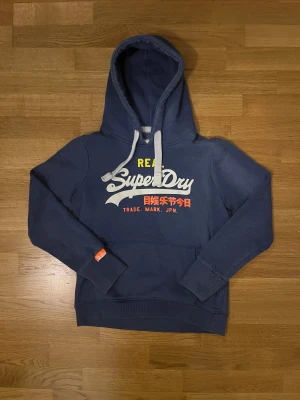 Superdry hoodie  - Fin blå superdry hoodie i storlek L men sitter identiskt som S eftersom de är L för ungdom. Mycket bra skick. Skriv för fler frågor 🙏🏼