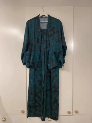 Grön/svart set  - Fint set i grönt/svart i sidenliknande material. Lite skavanker i form av rispor på byxorna både fram och bak (se bilder).