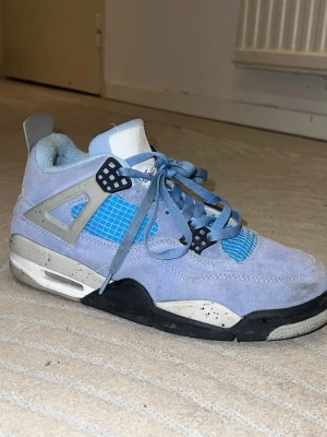 Nike Air Jordan 4 University Blue - Säljer ett par Nike Air Jordan 4 University Blue sneakers med ljusblå mocka, grå och svarta detaljer samt blå meshpaneler. Den är använd och lite smutsig men jag tvättar när du köper!
