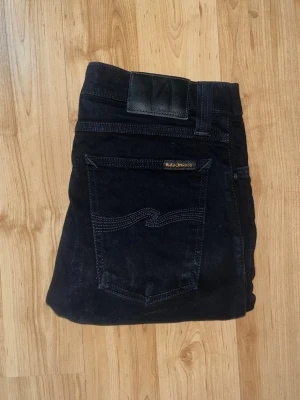 Nudie Jeans  - Svarta jeans från Nudie Jeans, modell High Kai. Slimmad passform med stretchig bomull. Midja 33cm, längd 99cm. JAG SKICKAR EJ FLER BILDER NÄR JAG BÄR JEANSEN! för bättre inblick i passformen rekommenderar jag att googla på modellnamnet. För storleksguide kolla måtten noggrant då jeansen alltid kan vara uppsydda heller krympta och jag ej tar emot returer :) s5,3