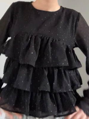 Glittrig volangblus - Jätte gullig svart blus med volanger & glitterprickar. Endast använd ett par gånger 💗 storlek 158/164 men sitter som XS 🌃 Perfekt till nyår