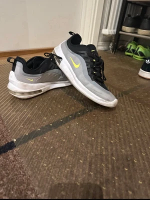 Nike Air Max sneakers grå/svart stolek 43 - Nike Air Max sneakers i grått och svart med neon-gula detaljer och logga. Skorna har snörning, synlig luftkudde i sulan och rund tå. Ovandelen är i syntet och mesh för bra ventilation. Snygg kontrast mellan färgerna och sportig vibe. Stolek 43