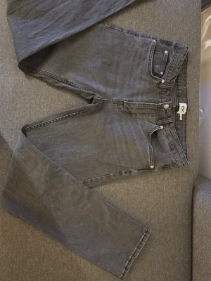 Grå jeans från 157, storlek 31/32 - Snygga grå jeans från 157 med klassisk femficksdesign och raka ben. Jeansen har en mörkgrå ton och är tillverkade i mjukt bomullsmaterial med lite stretch. Passar dig som gillar enkel och stilren look. Perfekt till sneakers eller boots.