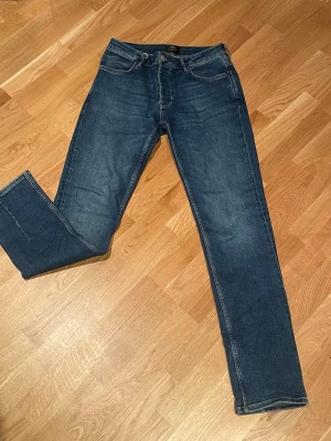 Mörkblå jeans från Neuw  - Säljer ett par mörkblå jeans från Neuw med rak passform och knappgylf. De här jeansen är gjorda i comfort stretch-denim och har stealth och kopparbeslag samt har Neuws karakteristiska tobaksfärgade sömmar. Detaljerad med bakre avsändardetalj och Neuws klassiska lagningssömmar och signatur-fob ring. Det är använda en gång och har inga tecken på användning. Nypris: 1500 kr / Storlek: W30, L34 