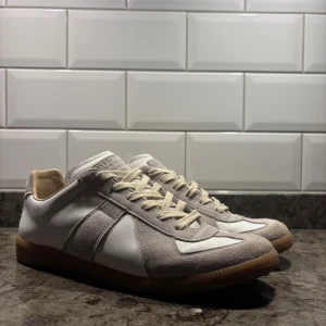 Vita och grå Maison Margiela Gats - Snygga sneakers i vit och ljusgrå färg. Ovandelen är i slät skinn och mocka, med beige insida och sula i brunt. Skorna har rund tå, platt sula och snörning i offwhite. Vänster sko kan upplevas som pyttelite mindre. Pris går att förhandlas vid snabb affär👍