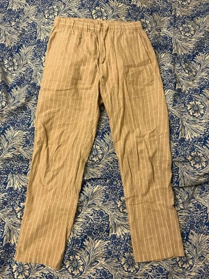 Linnebyxor - Randiga linnebyxor från H&M i storlek XS med i regular fit. Byxorna har elastisk midja med snörning. Perfekta för varma dagar och har en lätt, luftig känsla. Små små fläckar vid bakfickorna som man inte märker av