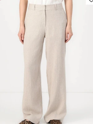 Beige linnebyxor med wide fit - Snygga beige linnebyxor med hög midja och breda ben. Byxorna har en klassisk look med diskret dragkedja och fickor fram. Perfekta för dig som gillar en chill och stilren vibe. Materialet är linne som ger en skön och luftig känsla.