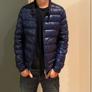 Blå moncler acorus - Säljer nu tyvärr min blå Moncler Acorus då den ej kommer till användning. Denna jackan är grym till både höst och vår och är enkel att matcha till ett par schyssta jeans! Den är i grymt skick och självklart äkta då den är köpt på NK för 2 år sedan för cirka 10 000kr. Jackan har hängt i garderoben ett tag nu och jag känner att det är gött att sälja denna grymma jacka till någon annan till ett rimligt pris. Jackan är i storlek 2 vilket motsvarar S/M. Ställ frågor om det finns något ni undrar över!