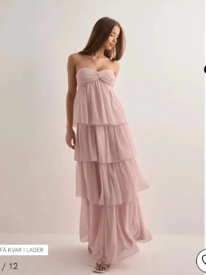 Rosa lång klänning med volanger. - Aldrig använd klänning från Nelly, pris lappen sitter kvar!  I XS