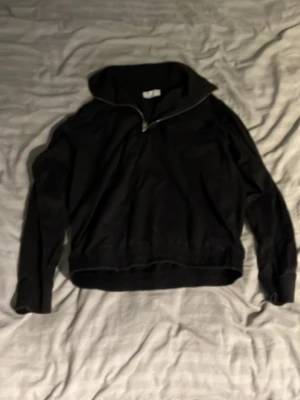 Tiger of Sweden långärmad tröja med half zip - Svart långärmad tröja med hög krage och half zip framtill. Tröjan har ribbade muddar vid ärmslut och nederkant, vilket ger en schysst passform. Perfekt för dig som gillar stilrena och enkla plagg med lite edge.