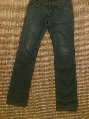 Svarta raka jeans från J Lindberg - Säljer ett par svarta jeans från J Lindberg  med klassisk femficksdesign och raka ben. Jeansen har normal passform och är tillverkade i slitstarkt jeanstyg. Perfekta för dig som gillar en enkel och tidlös look.