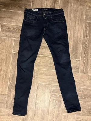 Replay Anbass Hyperflex mörkblå jeans, storlek 34 - Säljer ett par Replay Anbass Hyperflex jeans i mörkblå färg med snygga kontrastsömmar och klassisk femficksdesign. Modellen har smal passform och är tillverkad i stretchigt bomullsmaterial för extra komfort. Storlek: W34 L36. Perfekt för dig som gillar stilrena och moderna jeans. Hör av dig vid minsta intresse eller för fler bilder osv😁