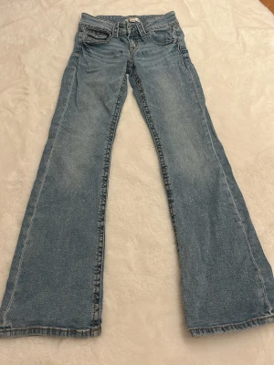 Blå bootcut jeans Gina Tricot 152 - Säljer ett par ljusblå bootcut jeans från Gina Tricot i storlek 152. Klassisk femficksmodell med knappgylf och bälteshällor. Jeansen har en snygg tvättad look och raka, utsvängda ben. Perfekta till sneakers eller boots. Nypris ca 350kr.💕