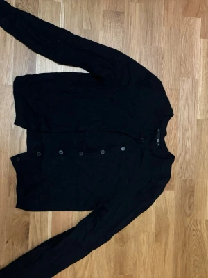 Svart kofta från 157 med knappar - Svart kofta från 157 i storlek M men är mer storlek s skulle jag säga. Koftan har långa ärmar och knäppning med svarta knappar framtill. Materialet känns mjukt.