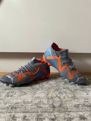 Puma Future Ultimate FG/AG Supercharge 42.5 - Original skor, Puma Future Ultimate FG/AG Supercharge. Skorna är i använt skick och fullt fungerande. Dessa skor är till användning för både naturgräs och konstgräs. Storlek 42.5.