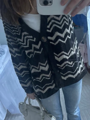 Svartvit kofta Missoni x Lindex XS - Säljer en svartvit kofta från Missoni x Lindex i storlek XS. Koftan har ett zigzagmönster, v-ringning och stora knappar framtill. Den är stickad och har två fickor samt lång ärm. Perfekt för dig som vill ha en statement piece i garderoben.