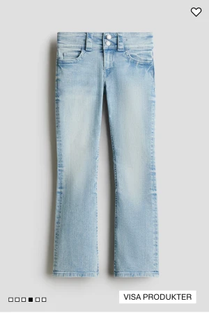 Bootcut ljusblå jeans med dubbla knappar - Snygga bootcut jeans i ljusblå tvätt med dubbla knappar i midjan och klassiska fem fickor. Jeansen har en lätt utsvängd passform nedtill och är tillverkade i mjukt denim-material som ger en skön känsla. Perfekta för dig som gillar retrovibbar och stilren look.