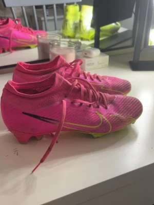 Nike rosa fotbollsskor Air Zoom - Går med på pris eller något byte. Säljer ett par grymt snygga Nike Air Zoom fotbollsskor i stark rosa med gula detaljer och svart swoosh. Skorna har snörning, platt sula med dobbar och är tillverkade i syntetmaterial med stickad känsla. Perfekt för dig som vill sticka ut på planen! De är sällsynta och säljs inte längre. Eller kanske för 3-6 tusen isåfall. Har ingen användning för dem längre. Kom privat och diskutera pris eller byte!😊